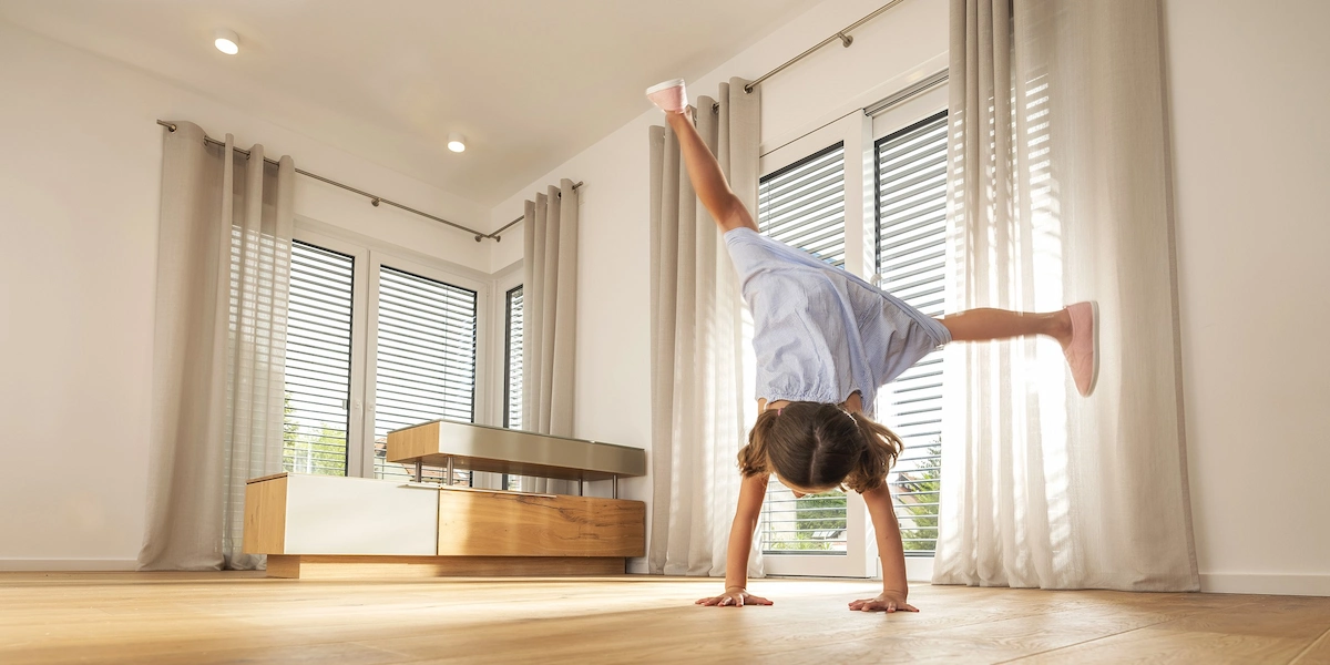 Hochwertiger Parkettboden in modernem Wohnraum. Der Holzboden wurde mit PALLMANN Produkten gepflegt, die im Parkettprofi Shop angeboten werden. Ein junges Mädchen schlägt ein Rad.